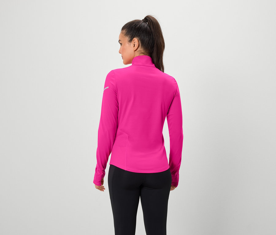 Kobieta tyłem do kamery ma na sobie różową bluzkę z długim rękawem i czarne legginsy.