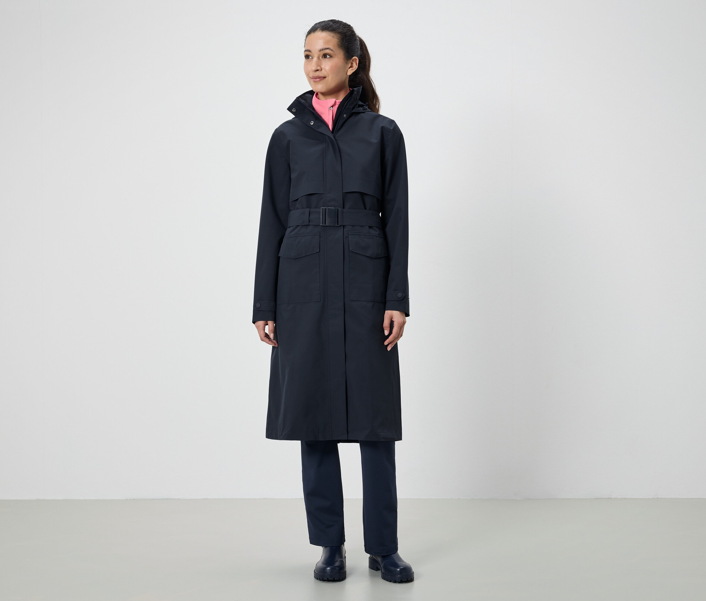 Kobieta ma na sobie długi czarny płaszcz z paskiem.