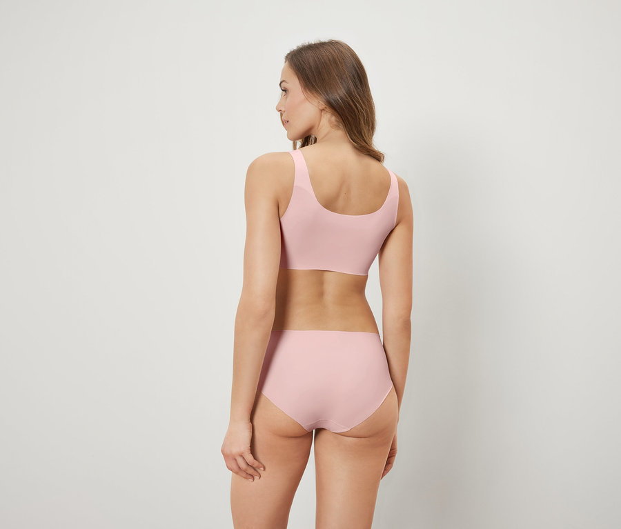 Kobieta tyłem do kamery ma na sobie różowy biustonosz i majtki.