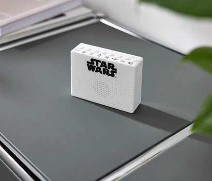 Biały głośnik Star Wars na szarej półce.