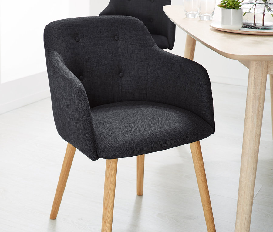 Dwa antracytowe krzesła tapicerowane przy stole.