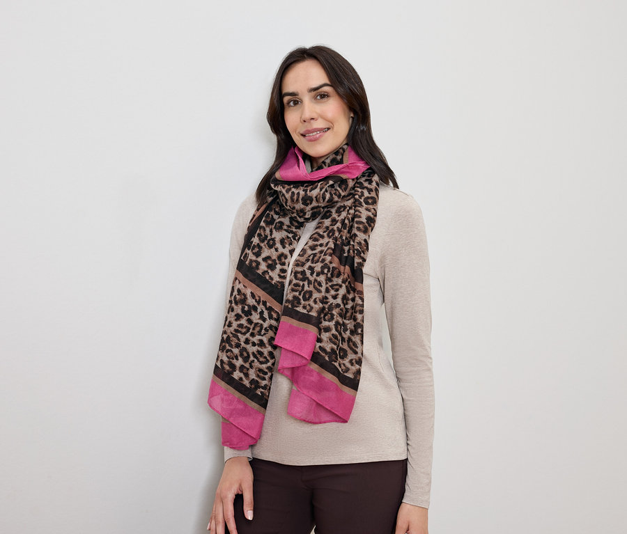 Kobieta o ciemnych włosach pozuje w szaliku w panterkę z różowymi akcentami.