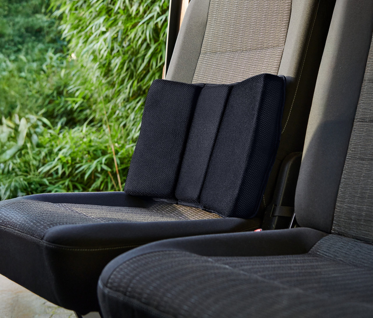 Czarna poduszka lędźwiowa umieszczona na siedzeniu samochodowym.