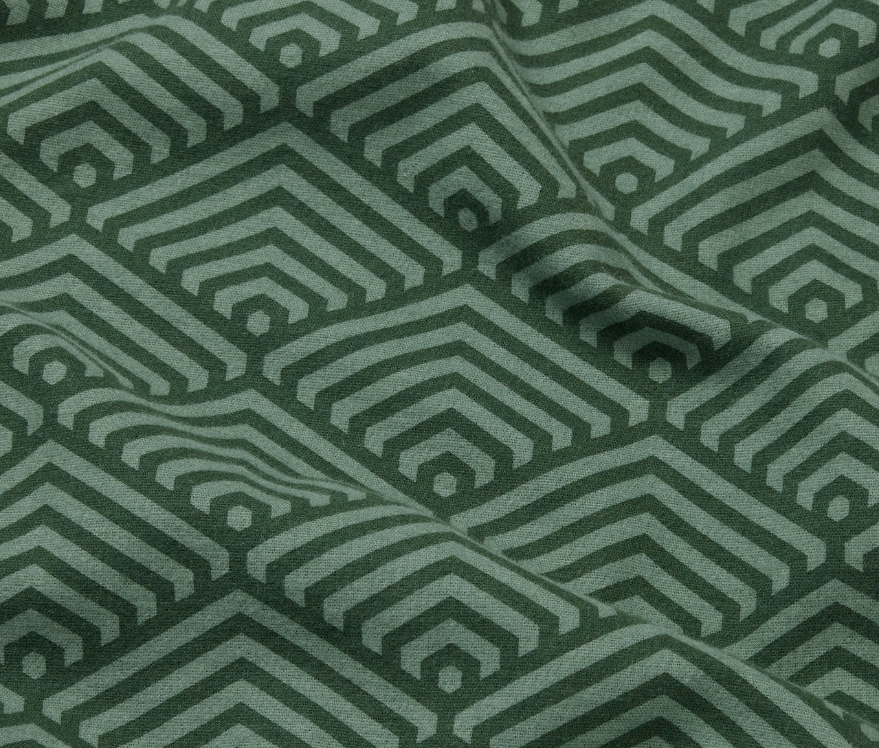 Zbliżenie na dwie zielone flanelowe poszewki na poduszki z geometrycznym wzorem.