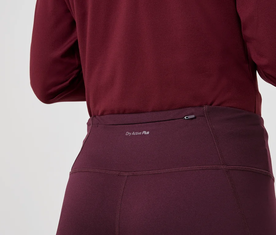 Zbliżenie na osobę ubraną w bordową koszulę z długim rękawem i legginsy z napisem "Dry Active Plus".
