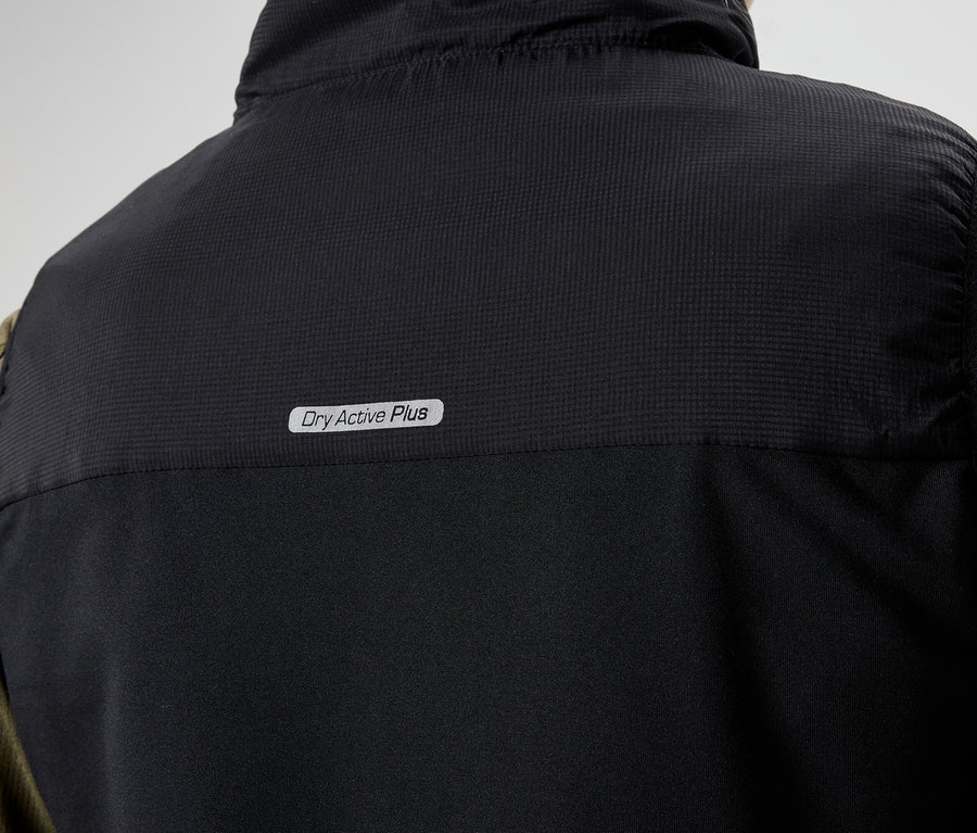 Zbliżenie na tył czarnej kamizelki z napisem "Dry Active Plus" nałożonej na oliwkowozieloną koszulę z długim rękawem.