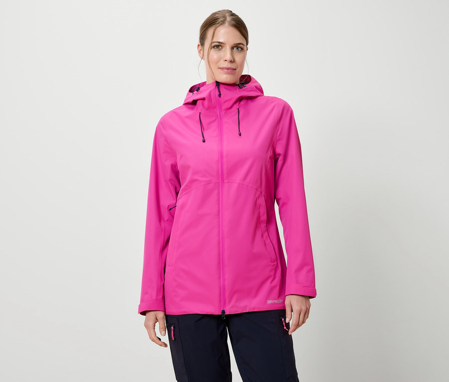 Kobieta ma na sobie różową kurtkę przeciwdeszczową z kapturem i granatowe spodnie na białym tle.