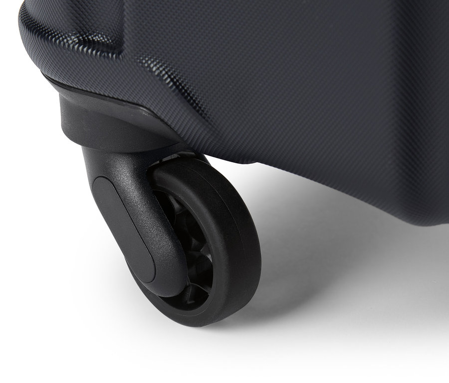 Szczegółowe ujęcie czarnego kółka walizki na białym tle.