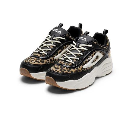 Dwa sneakersy FILA w panterkę z czarnymi detalami, białymi podeszwami i kremowymi sznurówkami.