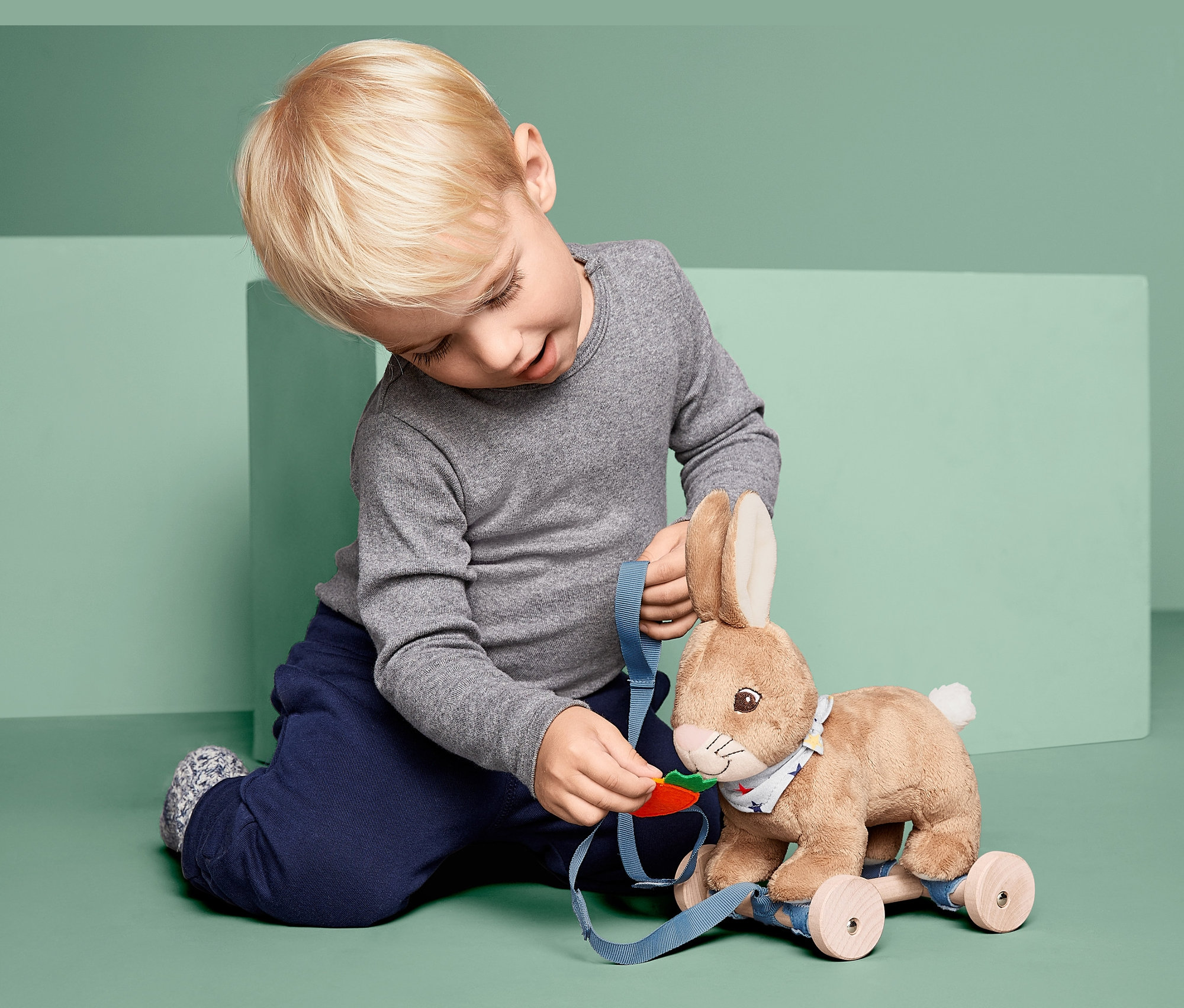 Chłopiec bawi się pluszowym skaczącym zajączkiem.