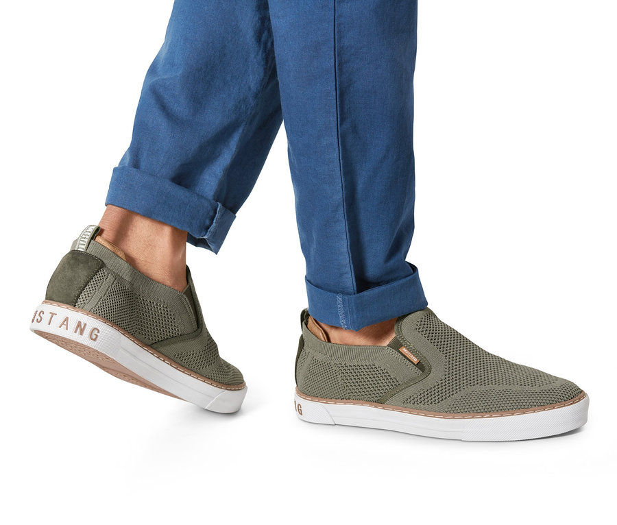 Osoba nosi khaki buty wsuwane »Mustang«. Buty mają białą podeszwę.