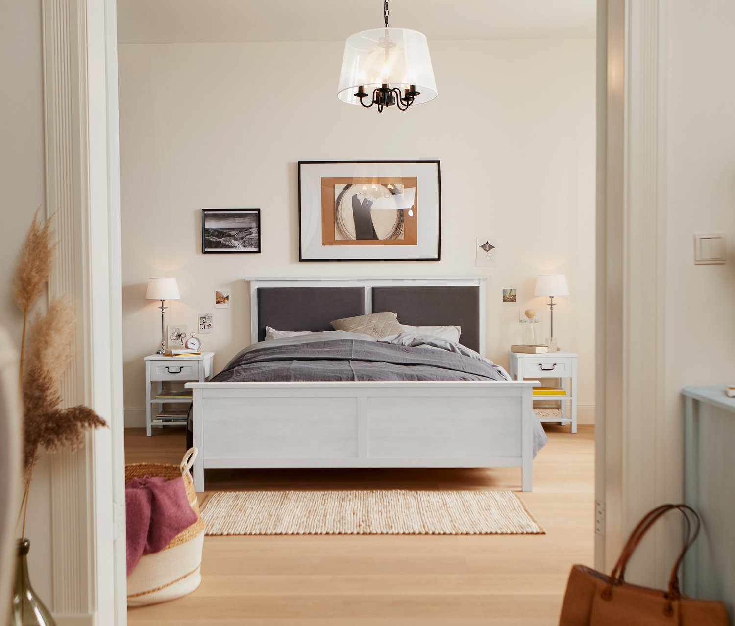 Sypialnia z łóżkiem z tapicerowanym zagłówkiem o wymiarach 160 x 200 cm, stolikiem nocnym z szufladą i lampą stołową z kloszem z tkaniny.