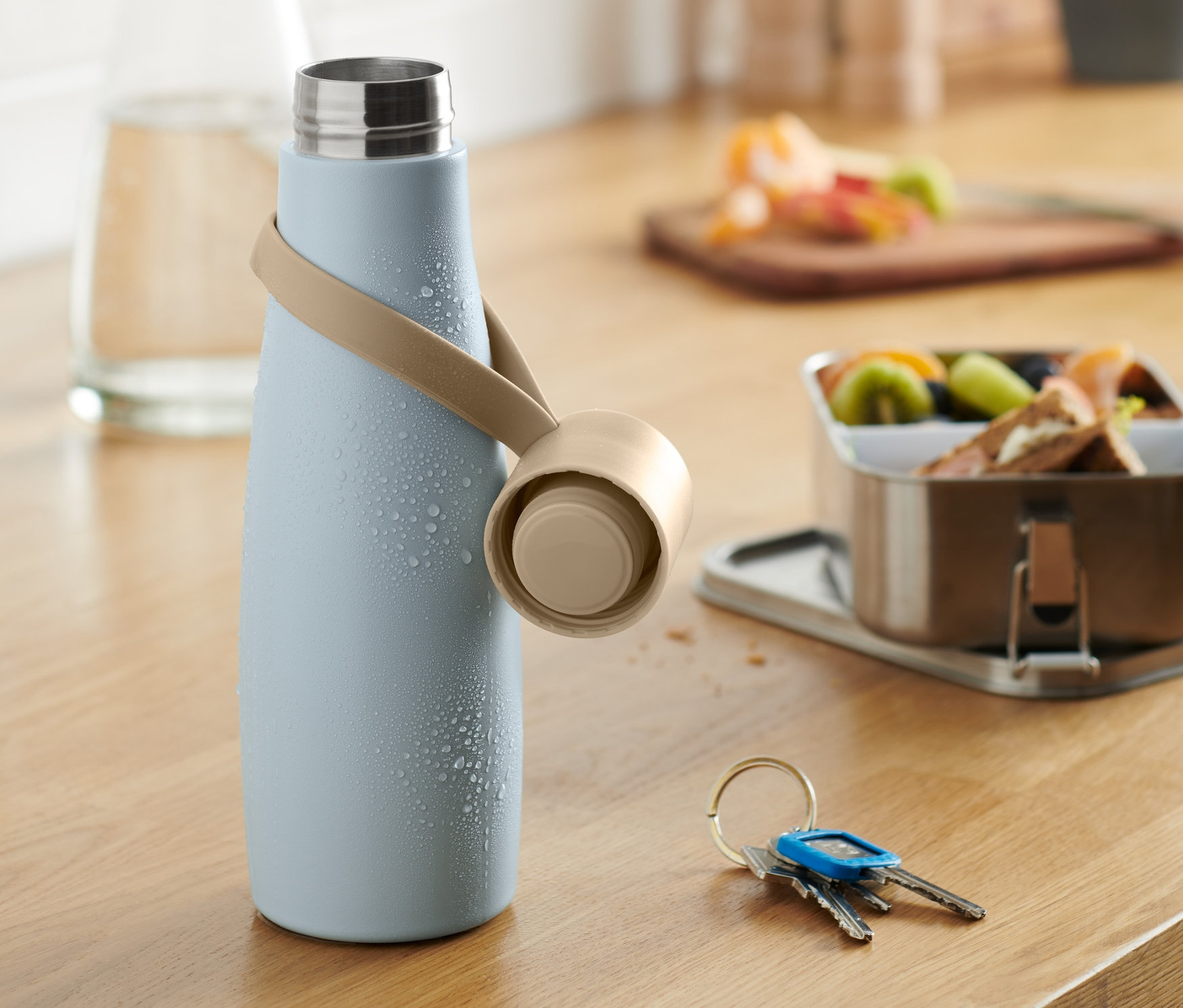 Jasnoniebieski bidon z beżowym paskiem na drewnianym blacie kuchennym.