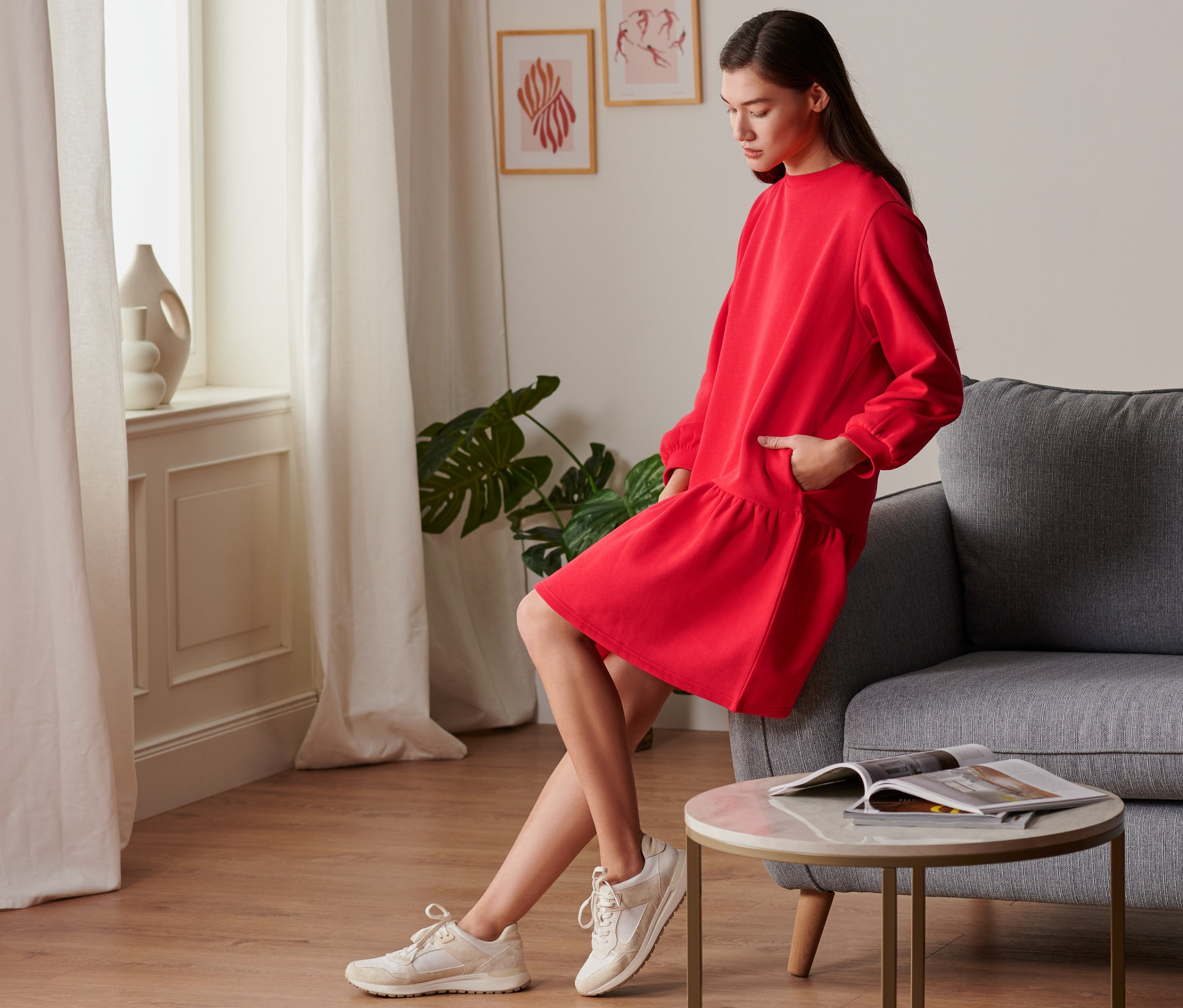 Kobieta pozuje w czerwonej sukience z dzianiny dresowej.