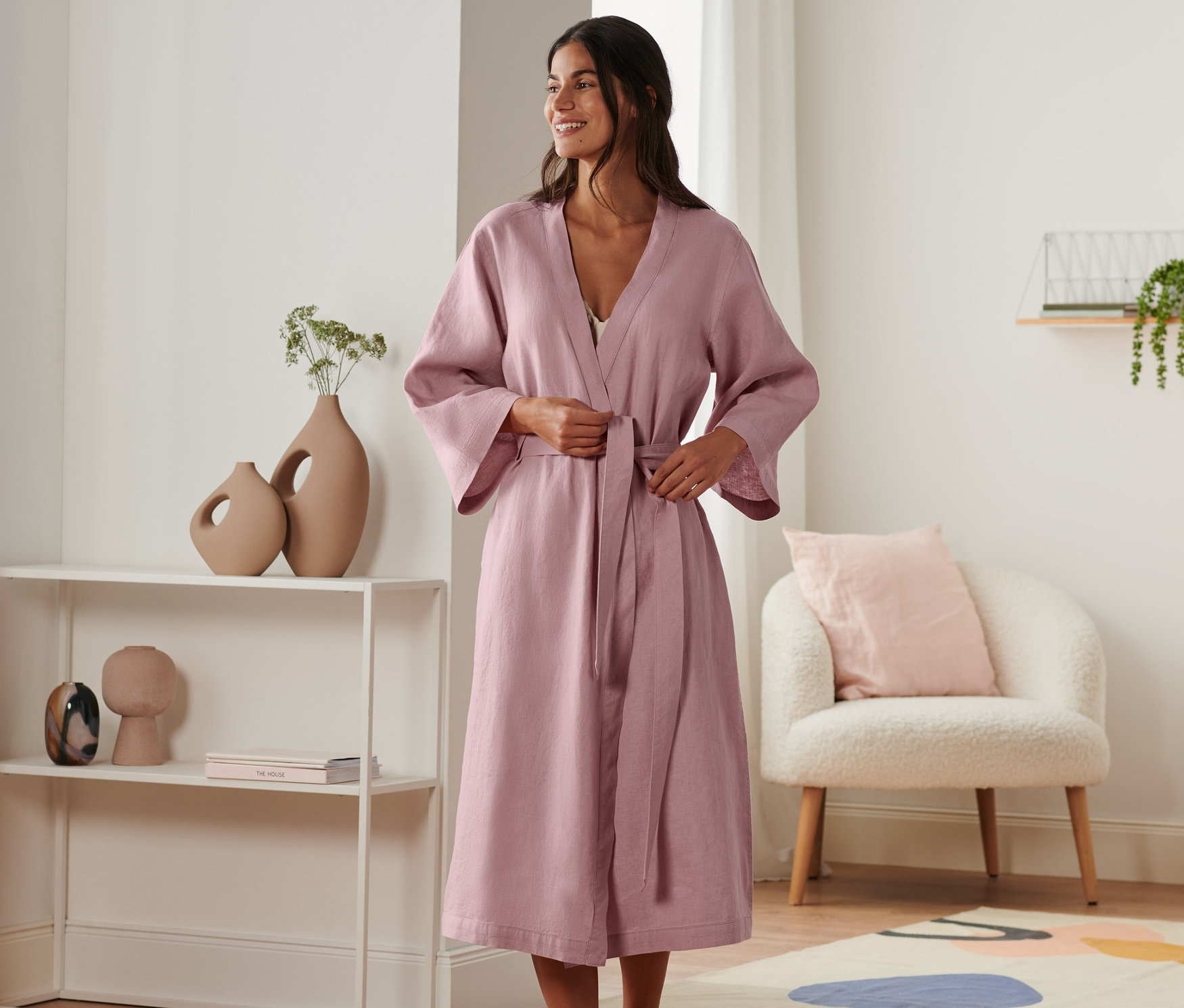 Kobieta wiąże lniany szlafrok w pokoju.