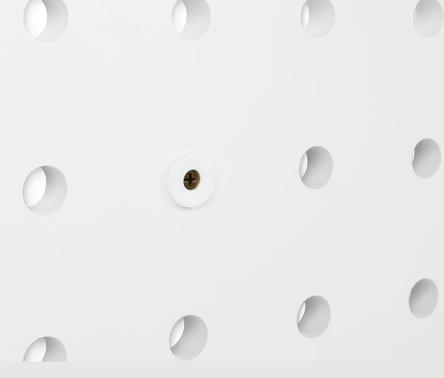 Detal białej, elastycznej półki ściennej z otworami i śrubą.