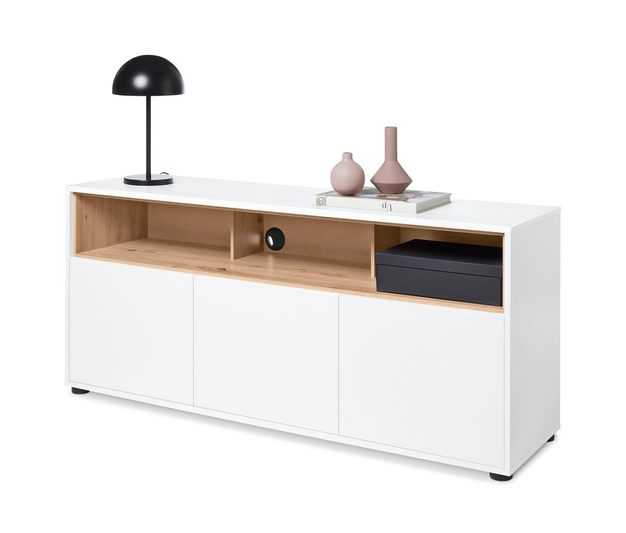 Biała szafka typu sideboard z detalami z dekoru dębowego, na której stoi lampa, wazony i książka.