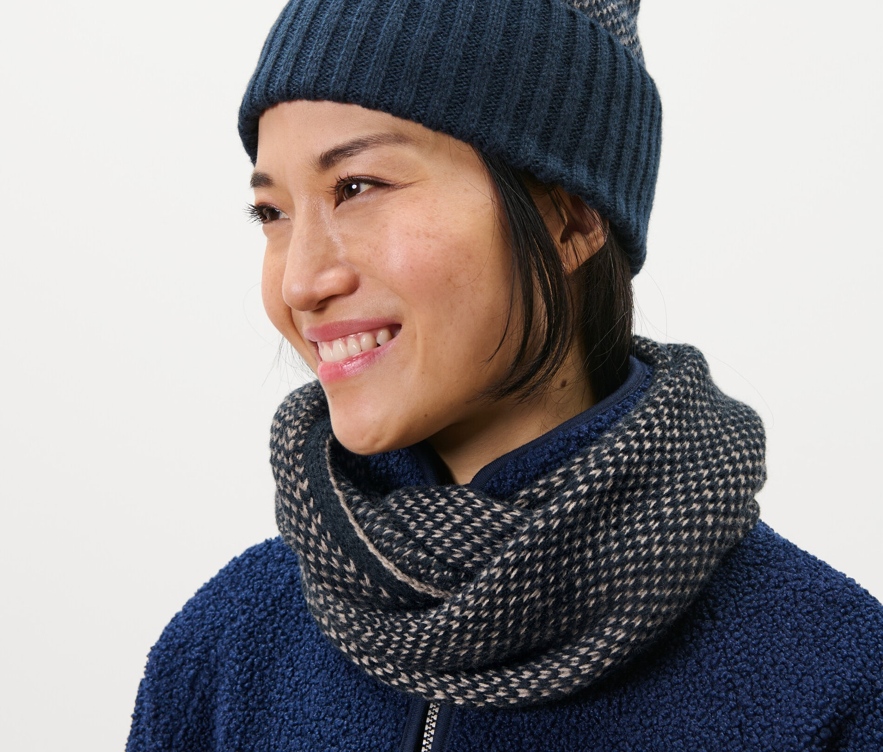 Kobieta ma na sobie komin z dzianiny i czapkę.