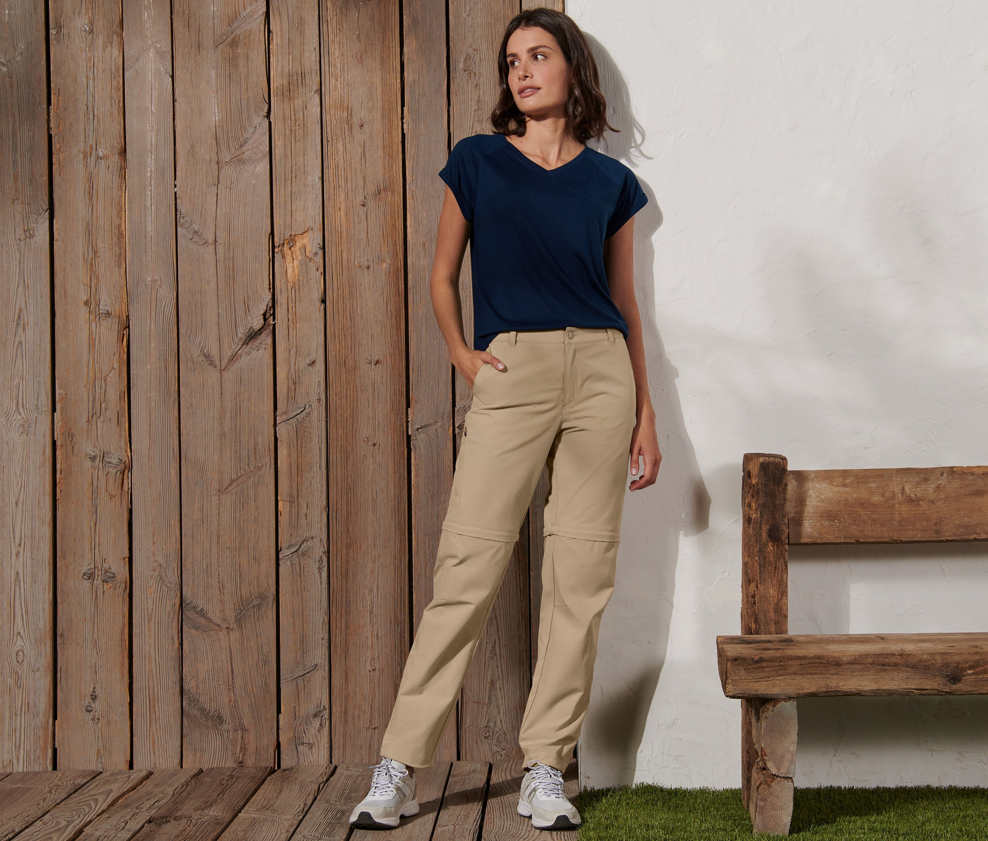 Kobieta pozuje w kremowych spodniach funkcyjnych 2 w 1 i niebieskiej koszulce.