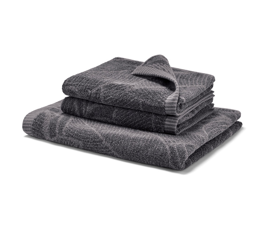 Ułożone na sobie żakardowy ręcznik kąpielowy i dwa żakardowe ręczniki w kolorze antracytowym.