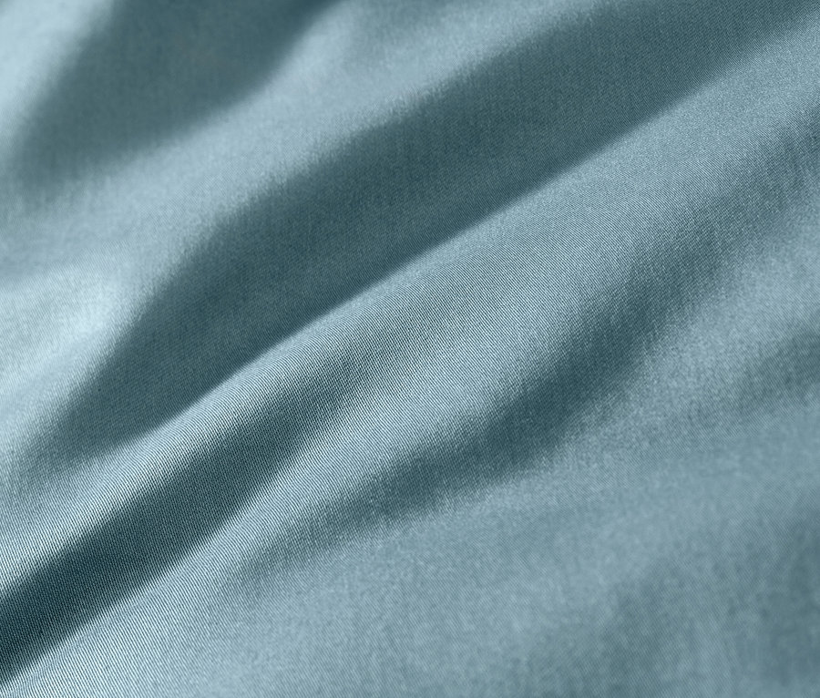 Zbliżenie na niebieską pościel z satyny bawełnianej.