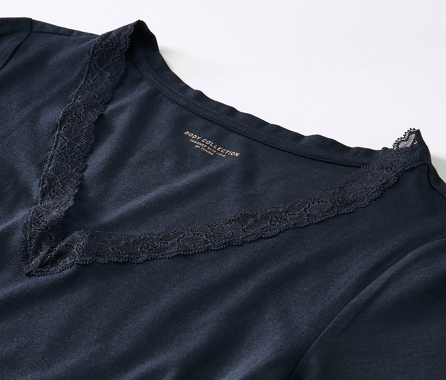 Zbliżenie granatowej piżamy z koronką przy dekolcie w kształcie litery V.