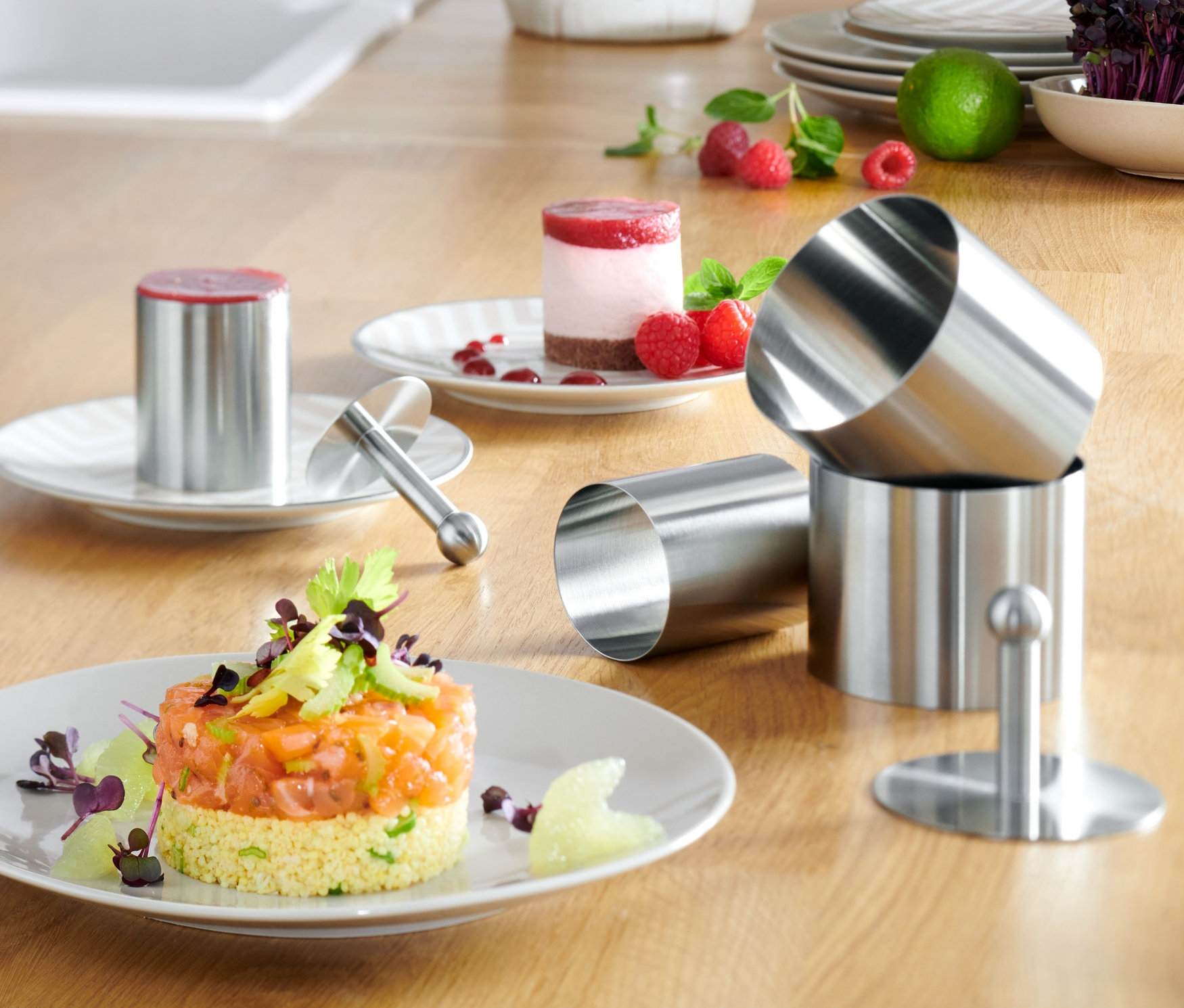 Na drewnianym blacie znajdują się 4 obręcze do przystawek i deserów, z których dwie służą do układania potraw na talerzach.