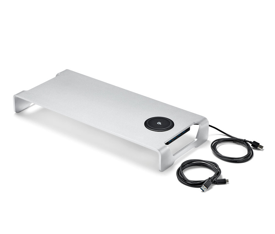 Srebrna podstawka pod monitor z bezprzewodową stacją ładowania i hubem USB oraz dwa czarne kable na białym tle.