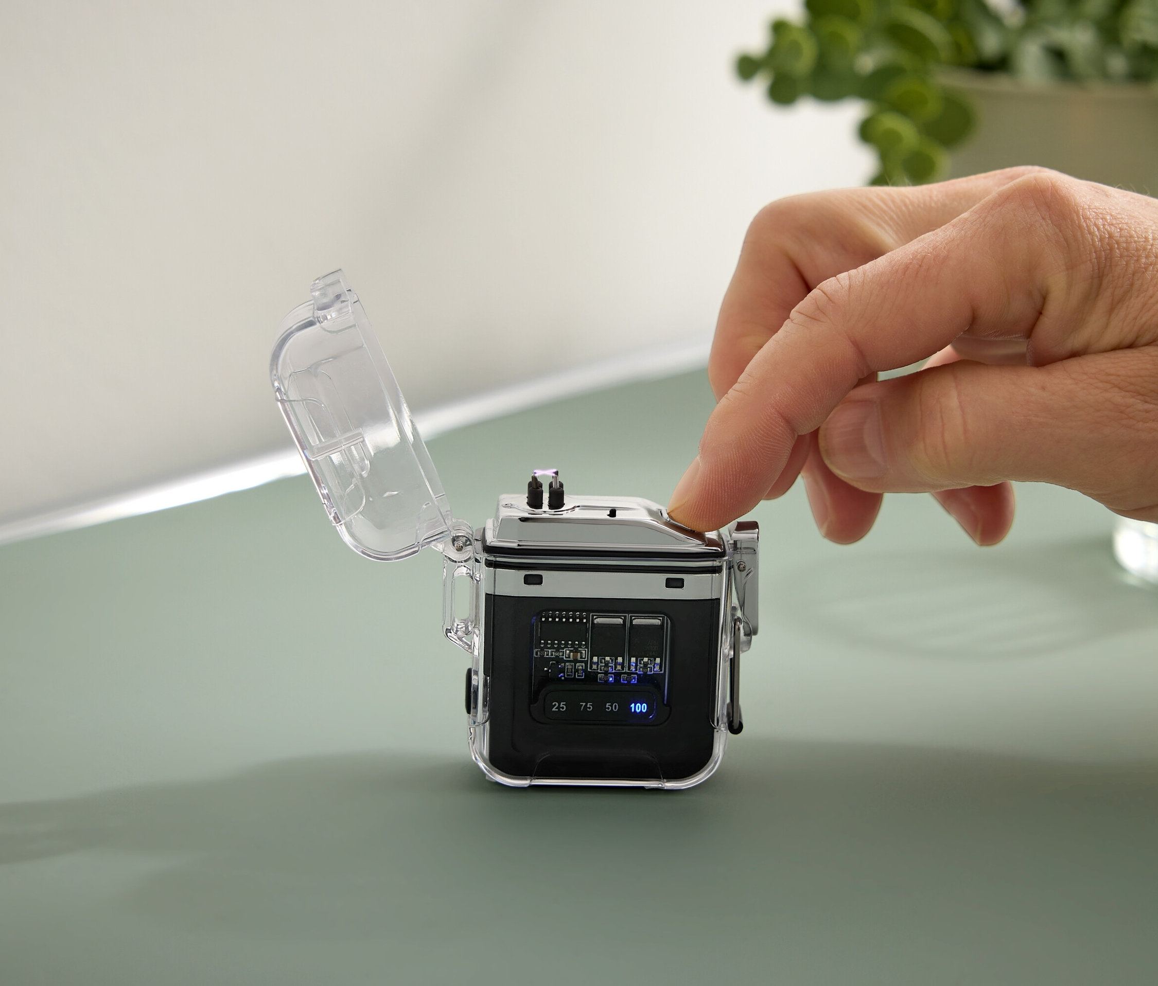 Dłoń naciska przycisk na małym czarnym urządzeniu z przezroczystą obudową.