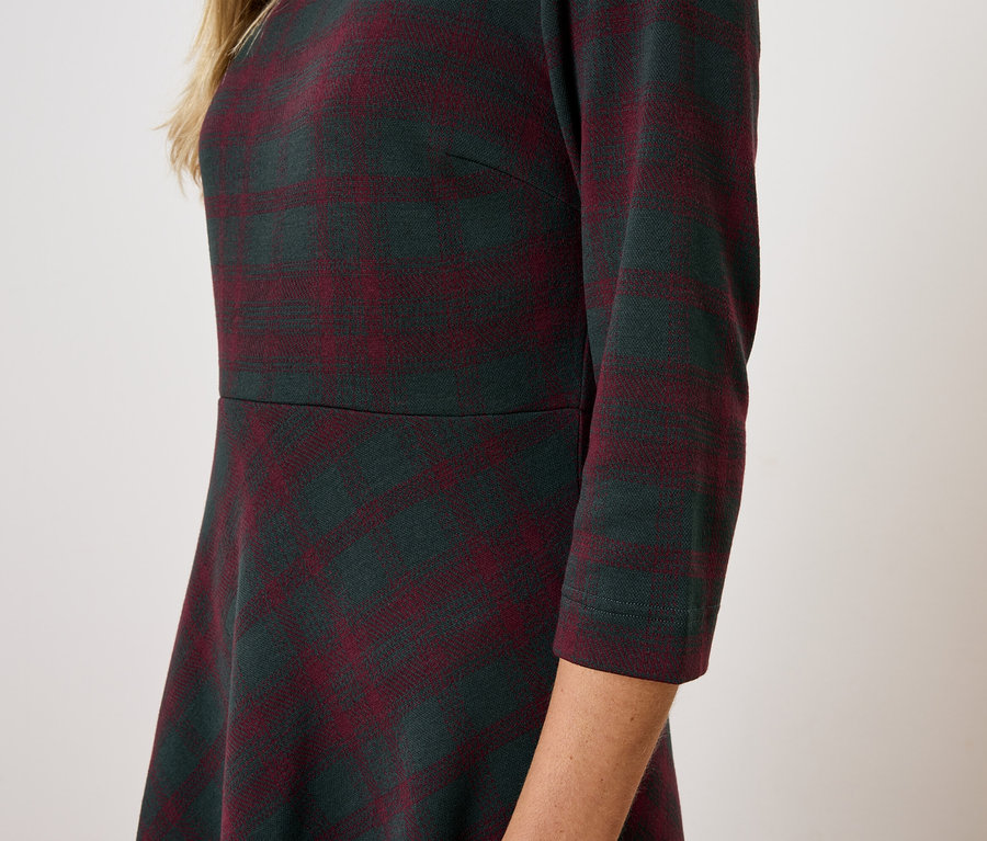 Widok z boku kobiety w sukience w kratę z rękawami trzy czwarte.