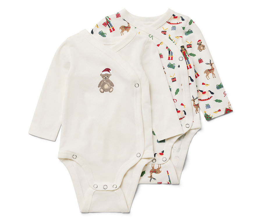 Dwa białe body z długim rękawem. Jedno ma brązowego misia w czerwonej czapce, a drugie motyw świąteczny.