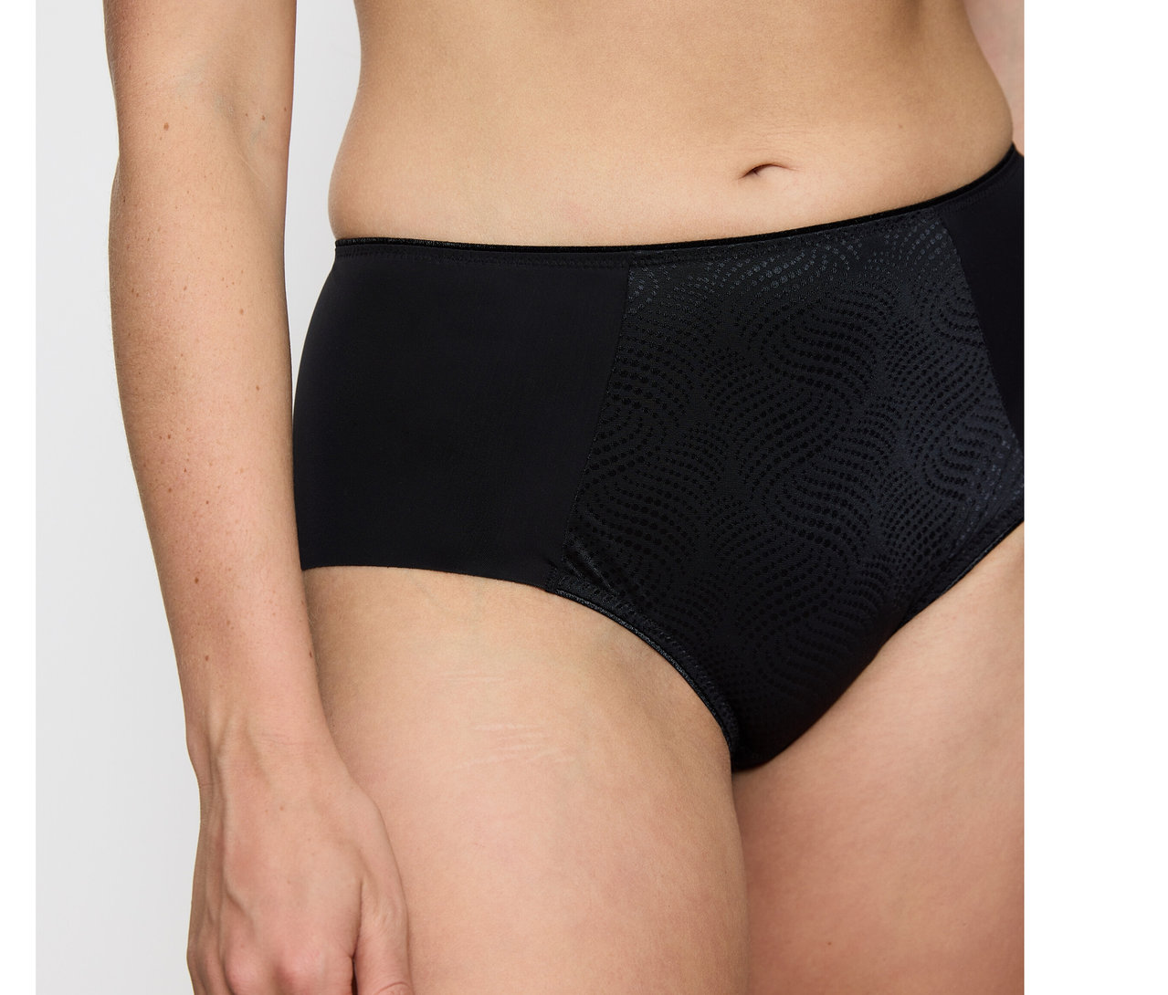Osoba nosi czarne figi typu hipster Triumph Essential „Minimizer Hipster X” z gładkimi bokami i teksturowanym, wzorzystym panelem z przodu.