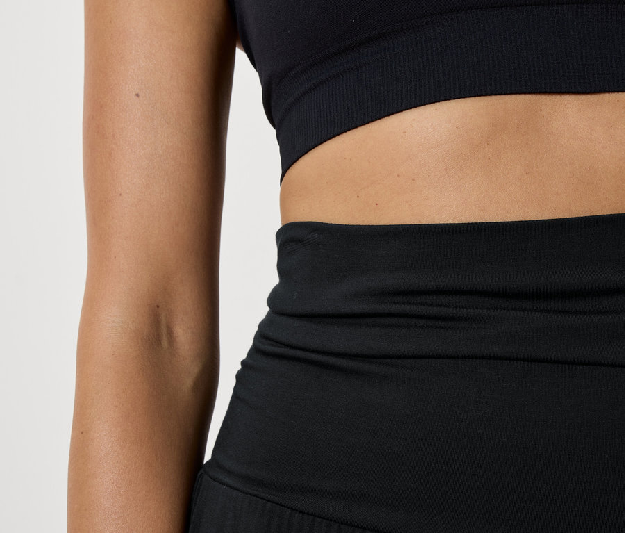 Zbliżenie na damską odzież sportową składającą się z czarnego biustonosza sportowego i legginsów.