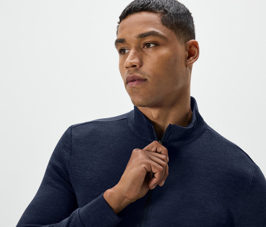 Mężczyzna rozpina granatową bluzę.