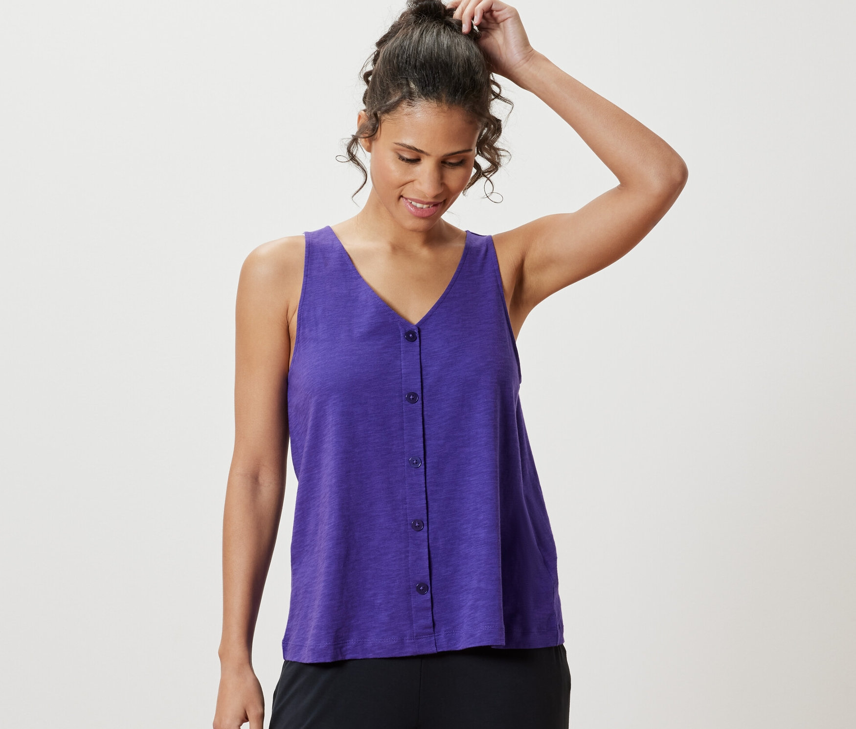 Kobieta poprawia włosy, ma na sobie liliowy top z zawartością modalu.