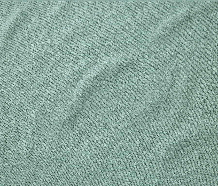 Zbliżenie na szałwiową koszulkę z fakturowaną powierzchnią.