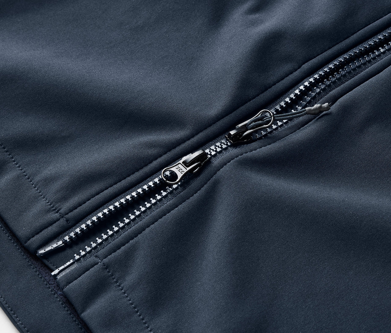 Detale granatowego płaszcza softshellowego ze srebrnym zamkiem błyskawicznym.