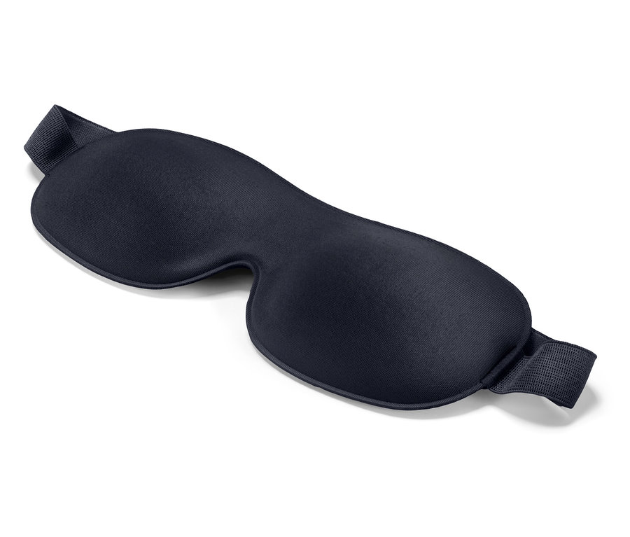 Na białym tle leży granatowa maska do spania.