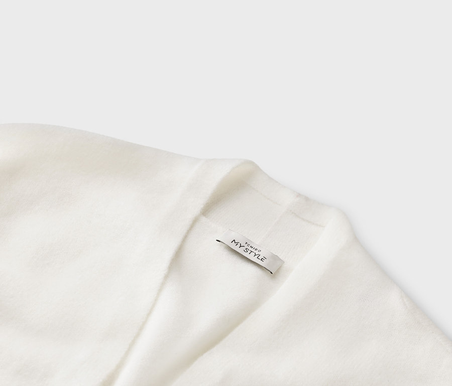 Zbliżenie na biały kardigan z metką z napisem „TCHIBO MY STYLE”.