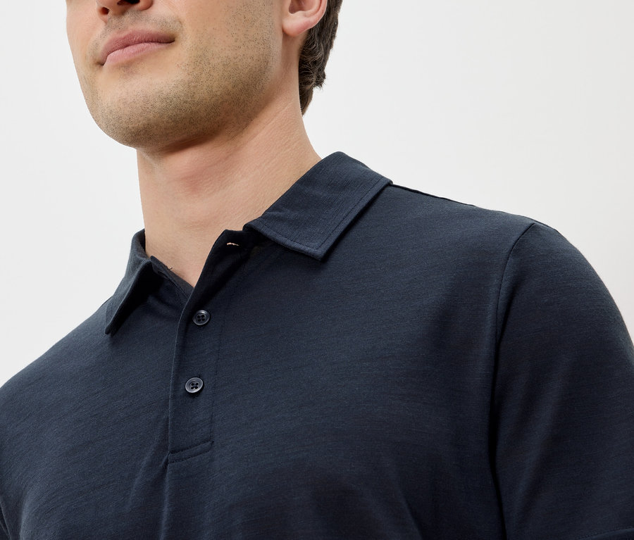 Zbliżenie mężczyzny w granatowej koszulce polo.