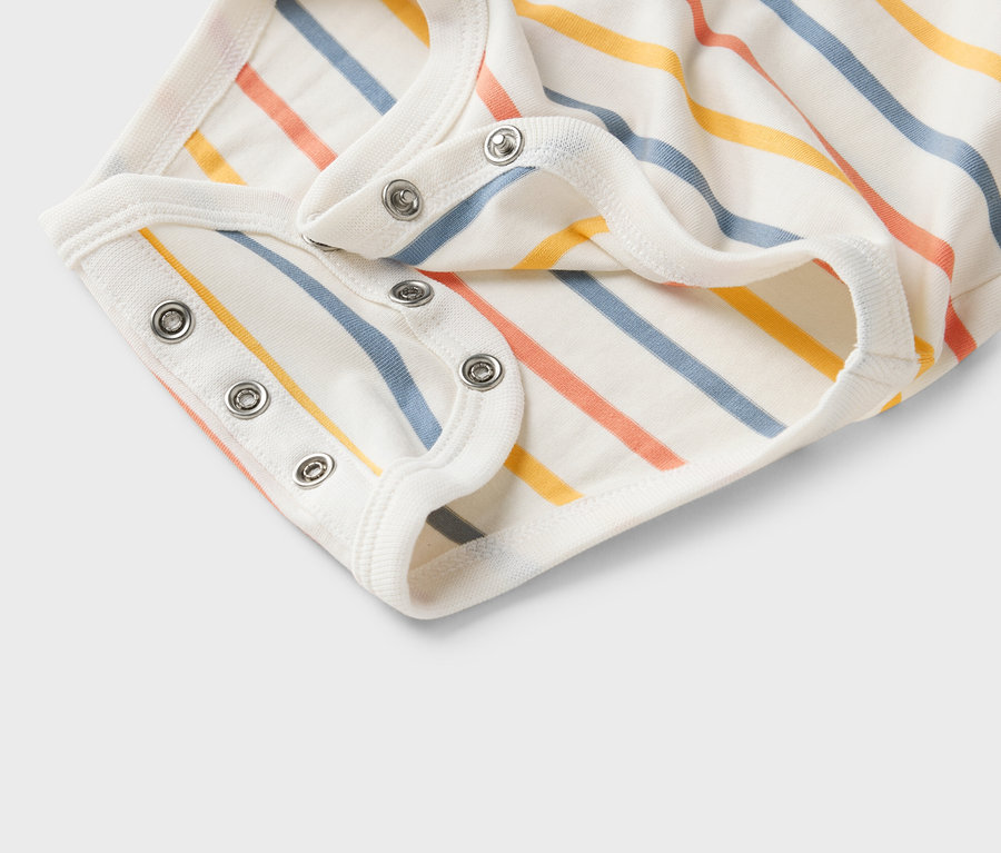 Zbliżenie białego body niemowlęcego w kolorowe paski z zatrzaskami.