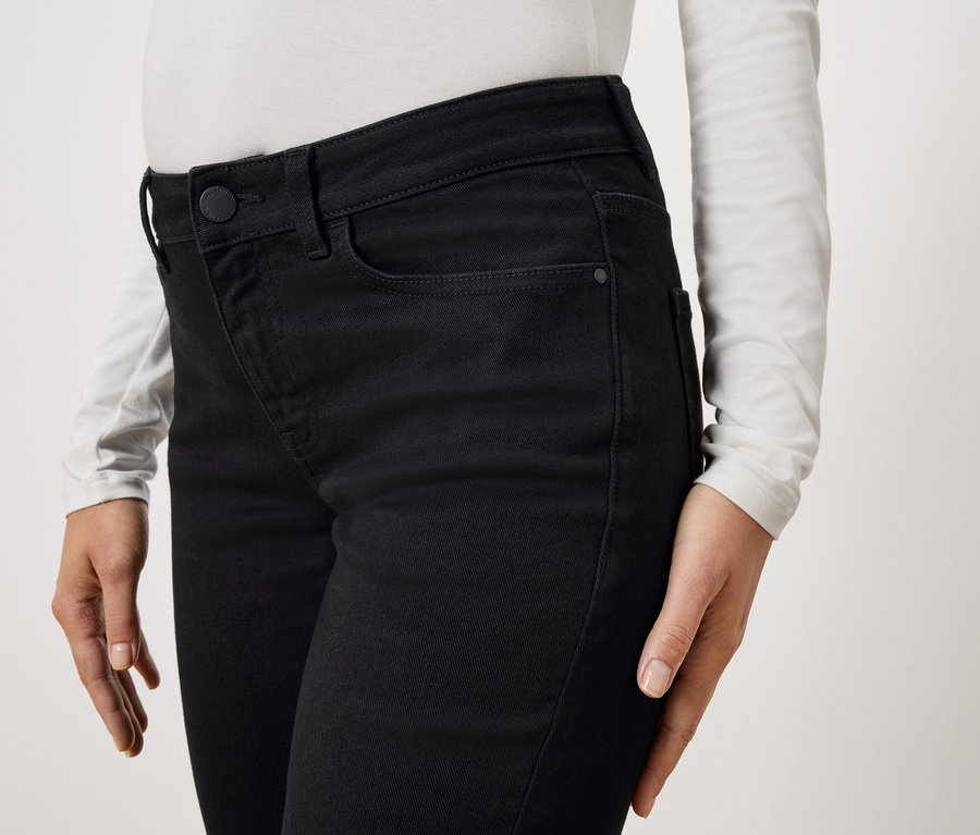 Zbliżenie osoby w czarnych dżinsach i białej bluzce z długim rękawem.