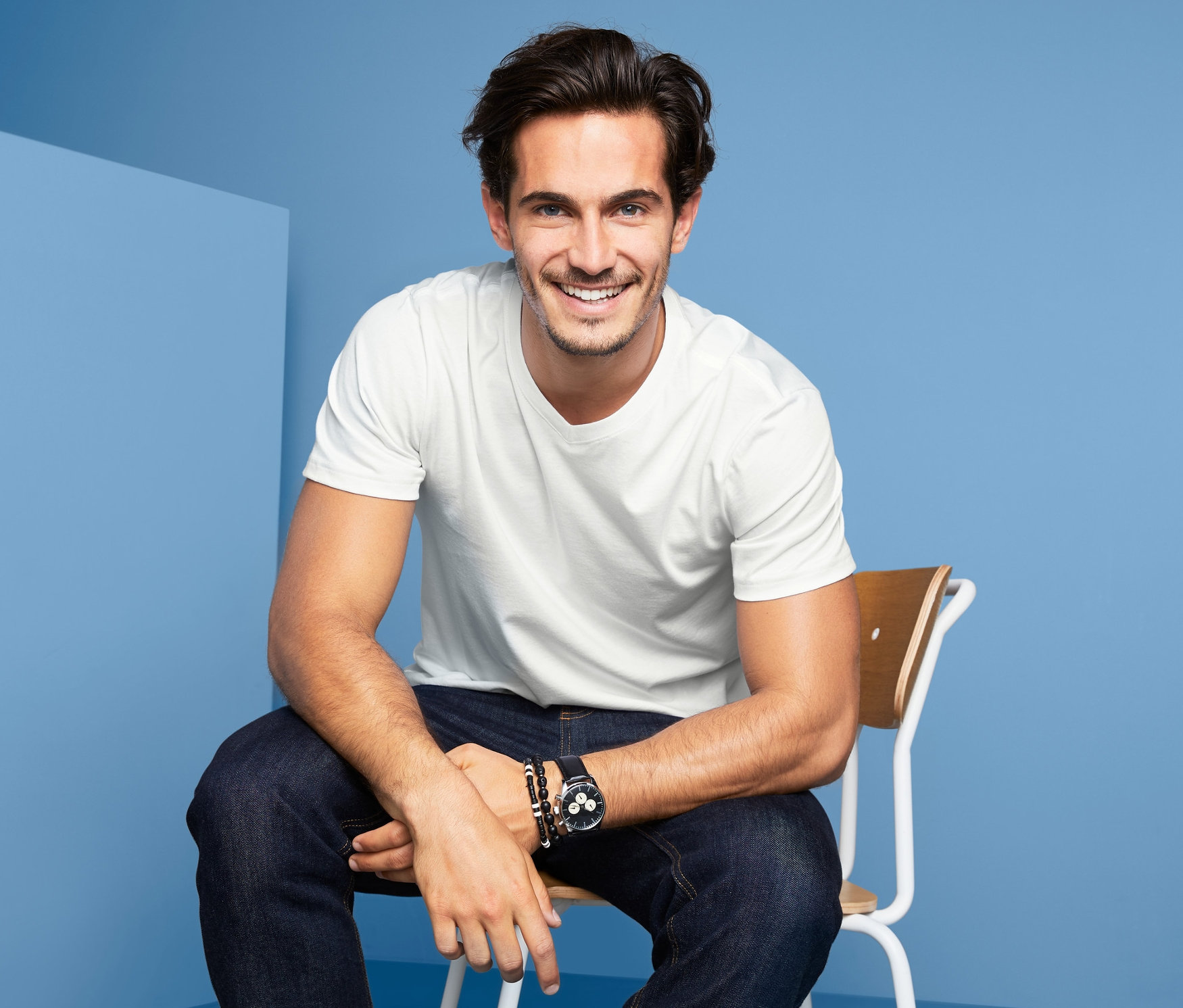 Mężczyzna siedzi na krześle, ubrany w białe T-shirty męskie gładkie, 2 sztuki .