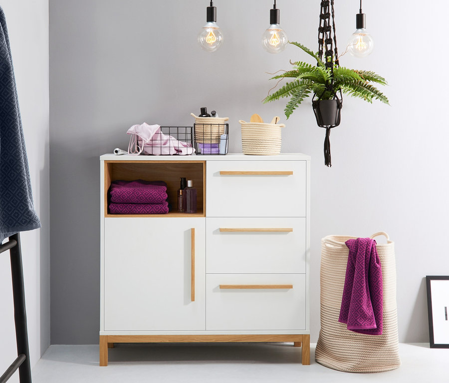 Dwa koszyki na akcesoria łazienkowe na komodzie z praniem i dekoracjami.