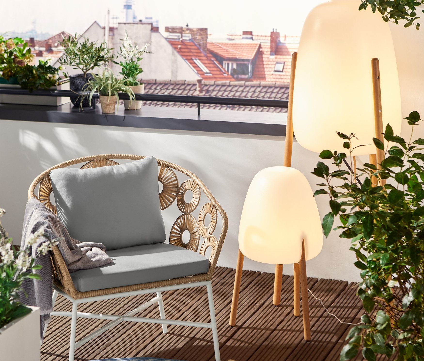 Na tarasie stoi fotel z kwiatowym wzorem i okrągły dywan ogrodowy. Na tacy leżą szklanki, karafka i miska z jagodami.