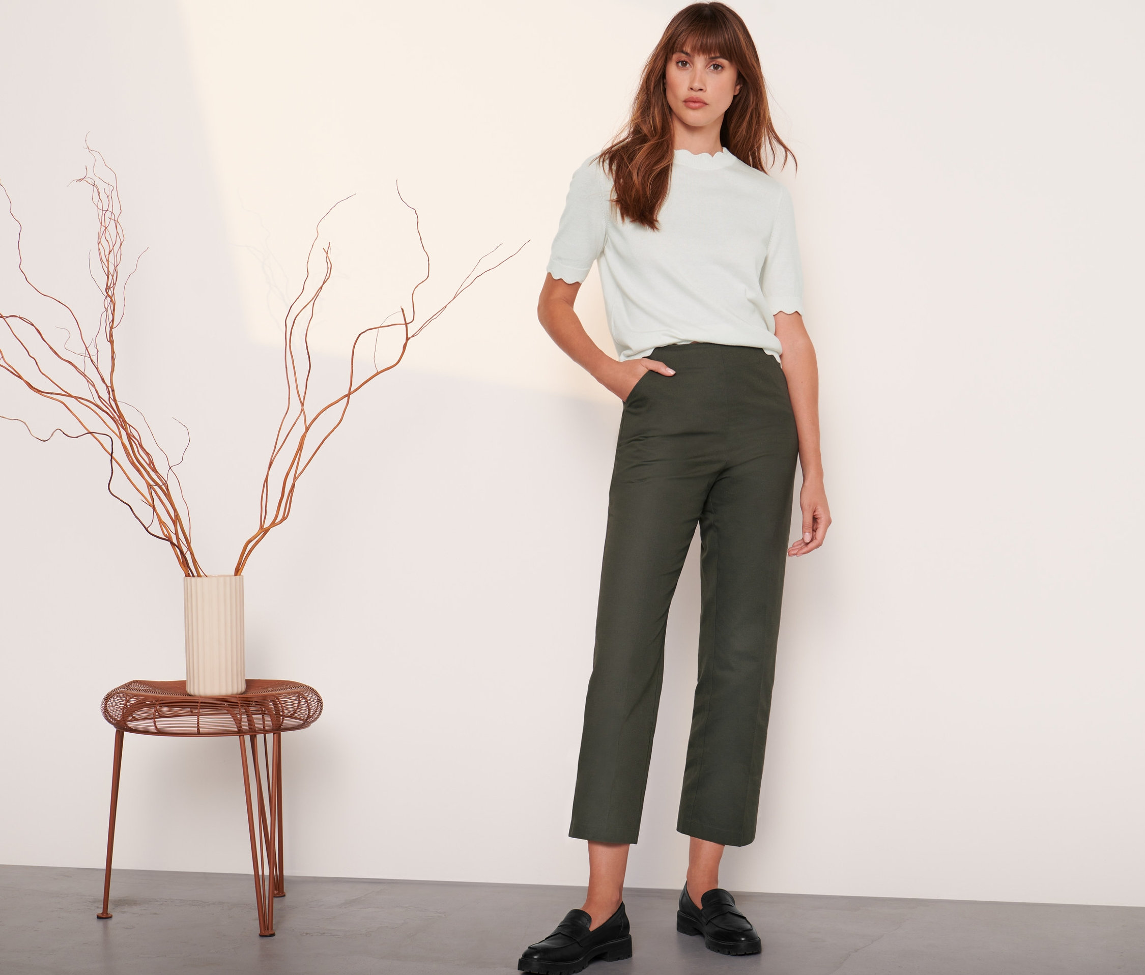 Kobieta stoi i pozuje w zielonych spodniach z tkaniny.