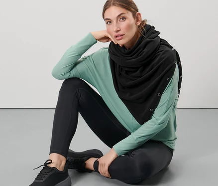 Kobieta siedzi na podłodze i ma na sobie czarny szal oversize 3 w 1.