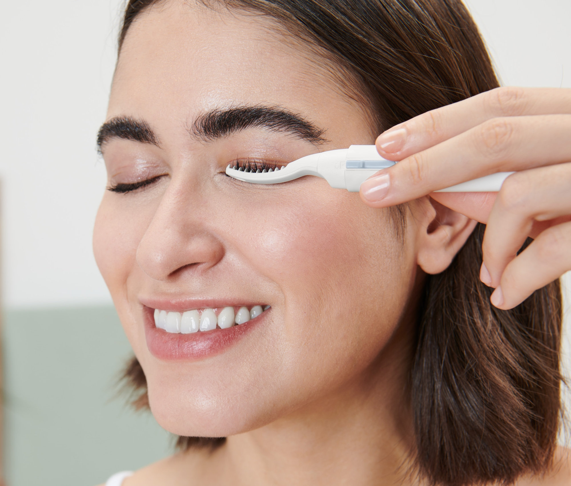 Kobieta używa podgrzewanej zalotki do rzęs.