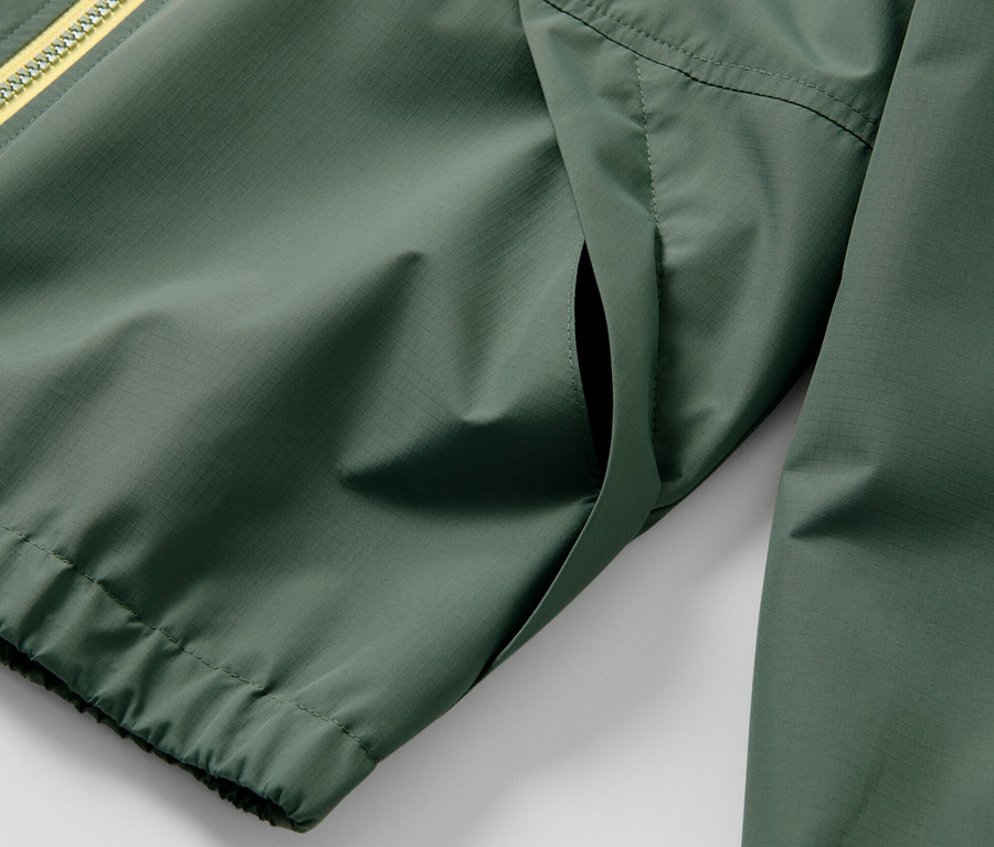 Zbliżenie na zieloną, sportową kurtkę funkcyjną dla dzieci z żółtym zamkiem błyskawicznym.