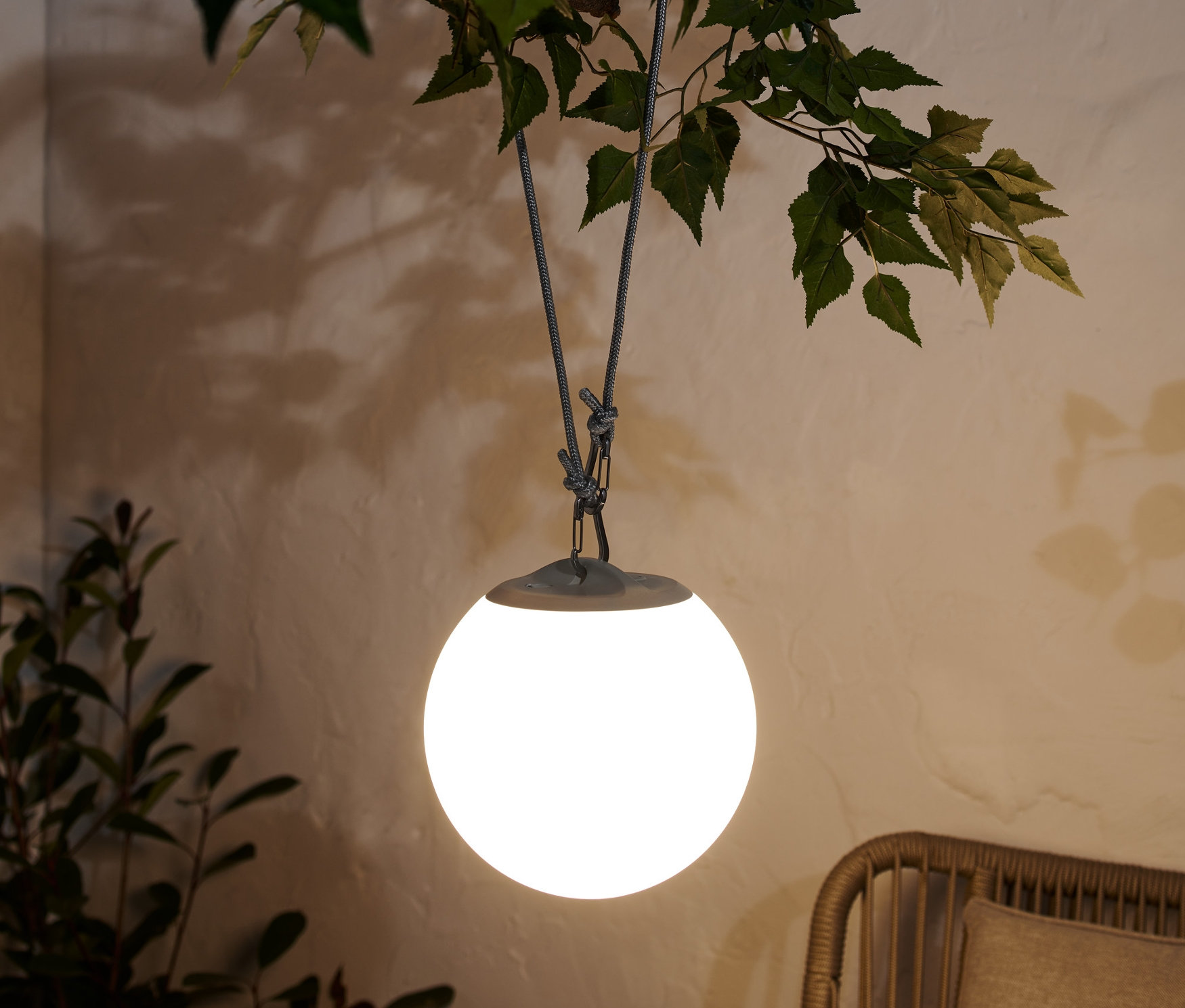 Akumulatorowa lampa wisząca LED zwisa z gałęzi drzewa.